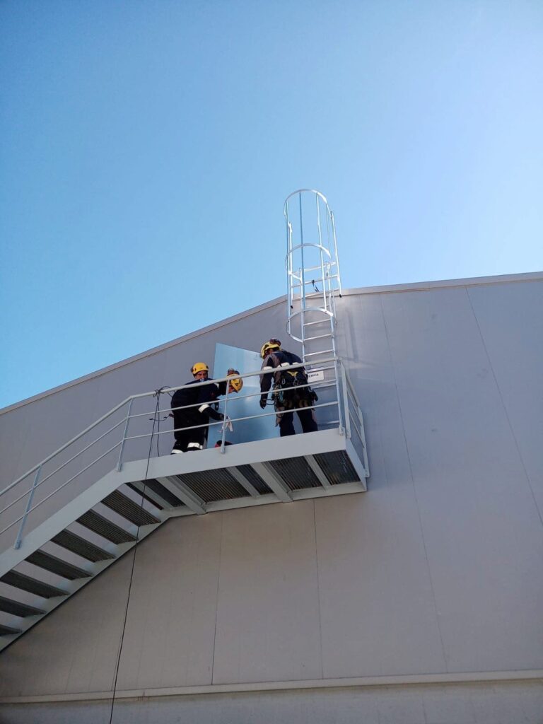 Escalera fija de servicio en nave industrial.
