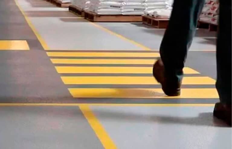 Paso de cebra pintado en amarillo sobre pavimento industrial.