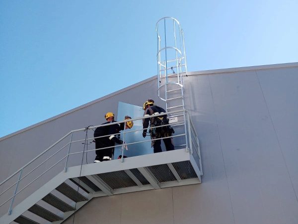 Escalera fija de servicio en nave industrial.